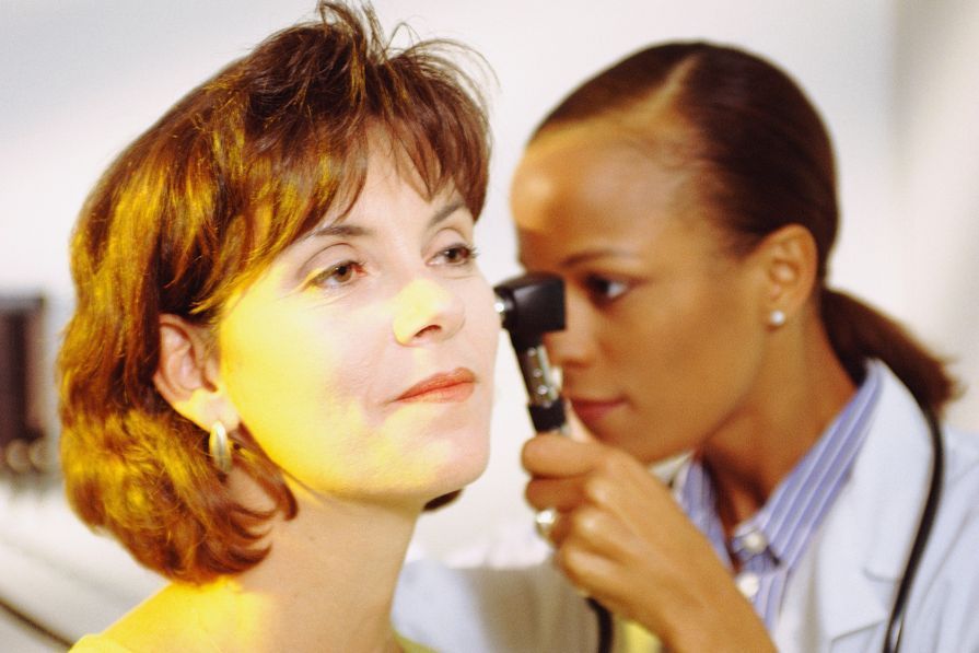 Médico examinando o ouvido do paciente com um otoscópio em um consultório médico.