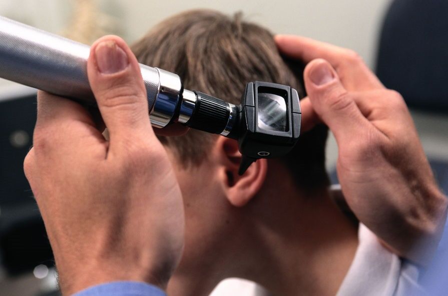 Médico examinando o ouvido de um paciente com um otoscópio.