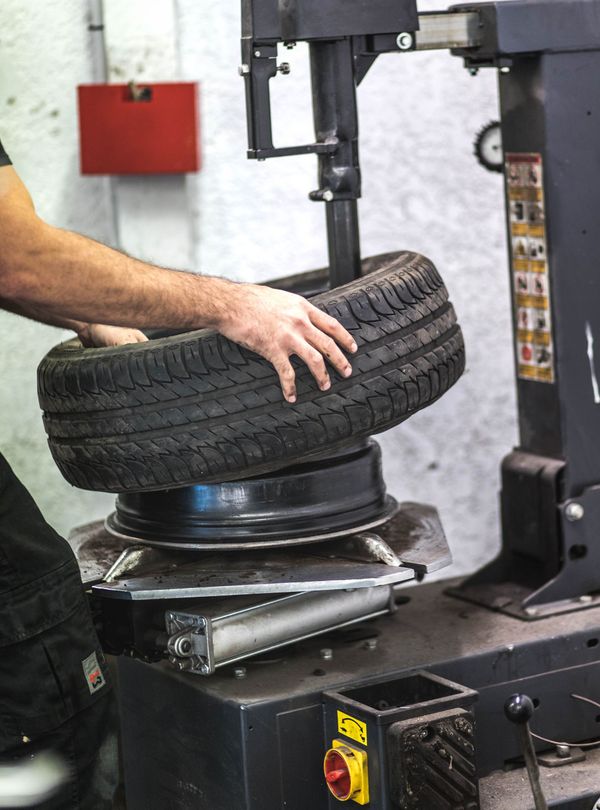 Une personne utilise une machine à pneus pour démonter un pneu d'une jante dans un garage.