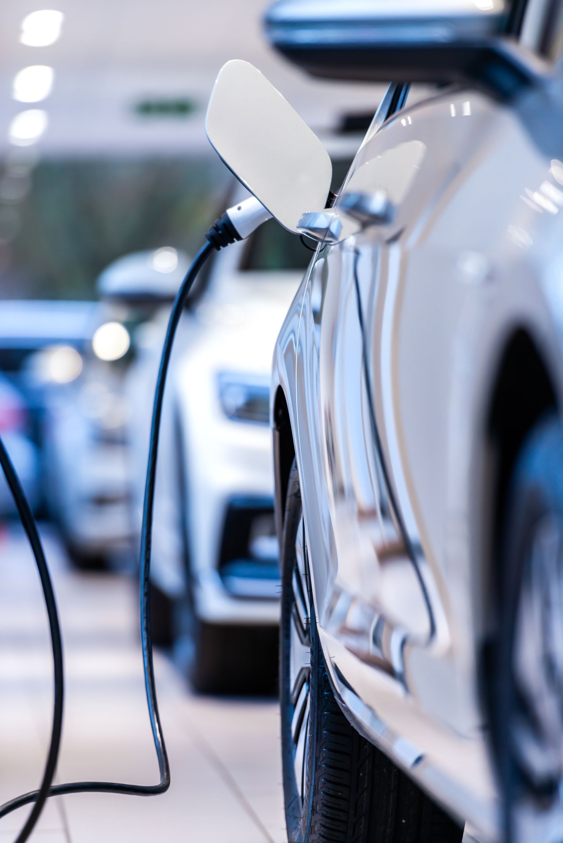 Voiture électrique blanche en charge dans une salle d'exposition, câble noir connecté.