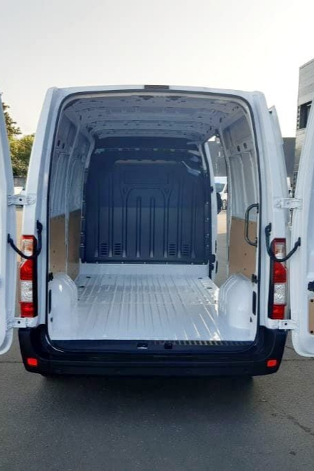 Fourgonnette blanche, portes arrière ouvertes, intérieur vide.