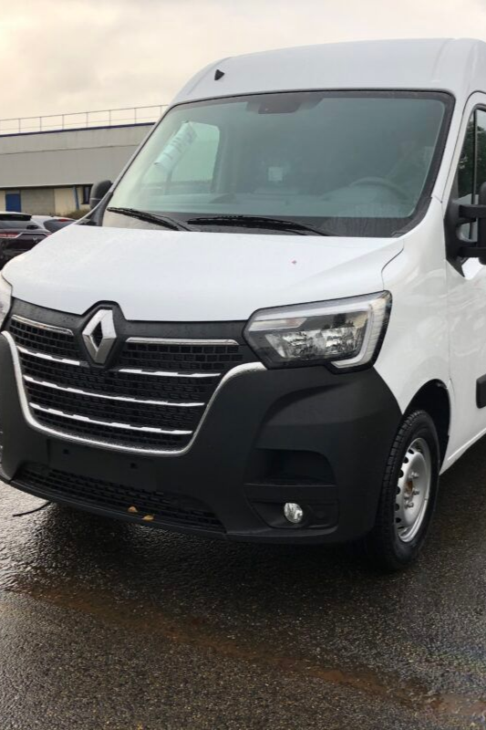 Fourgon Renault Master blanc, vue de face, stationné sur chaussée mouillée.