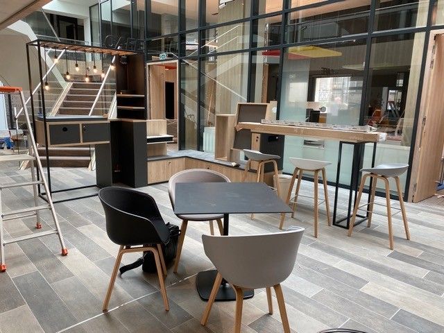 Salon de bureau moderne avec chaises, table ronde, tabourets et salles de réunion vitrées