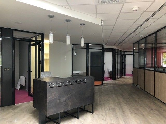 Intérieur de bureau moderne avec des pièces vitrées, du parquet et un comptoir d'accueil sombre.