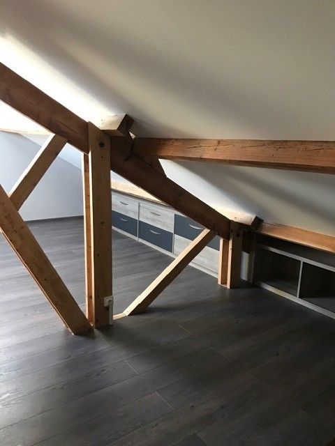 Rambarde de loft avec poutres en bois, mur blanc et sol foncé dans un intérieur moderne