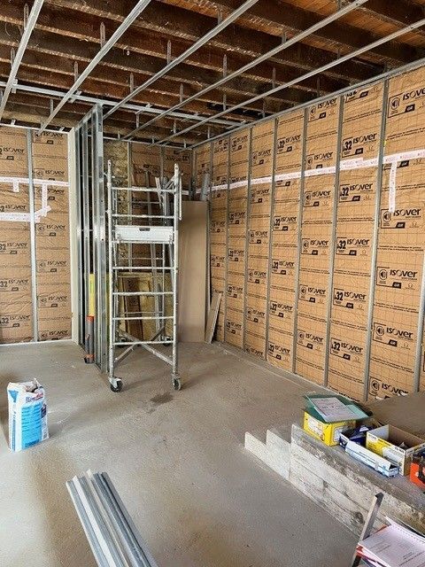 Intérieur d'un chantier de construction avec isolation en plaques de plâtre, échafaudages métalliques et charpente de plafond en cours de réalisation