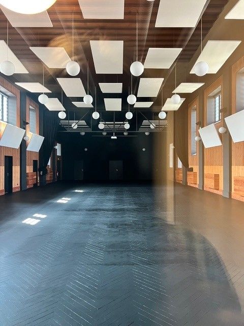 Hall intérieur vide avec poutres en bois, luminaires suspendus et grandes fenêtres
