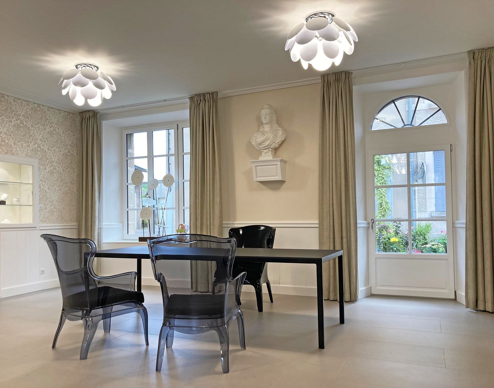 Salle à manger élégante avec table et chaises noires, murs, fenêtres et plafonniers couleur crème