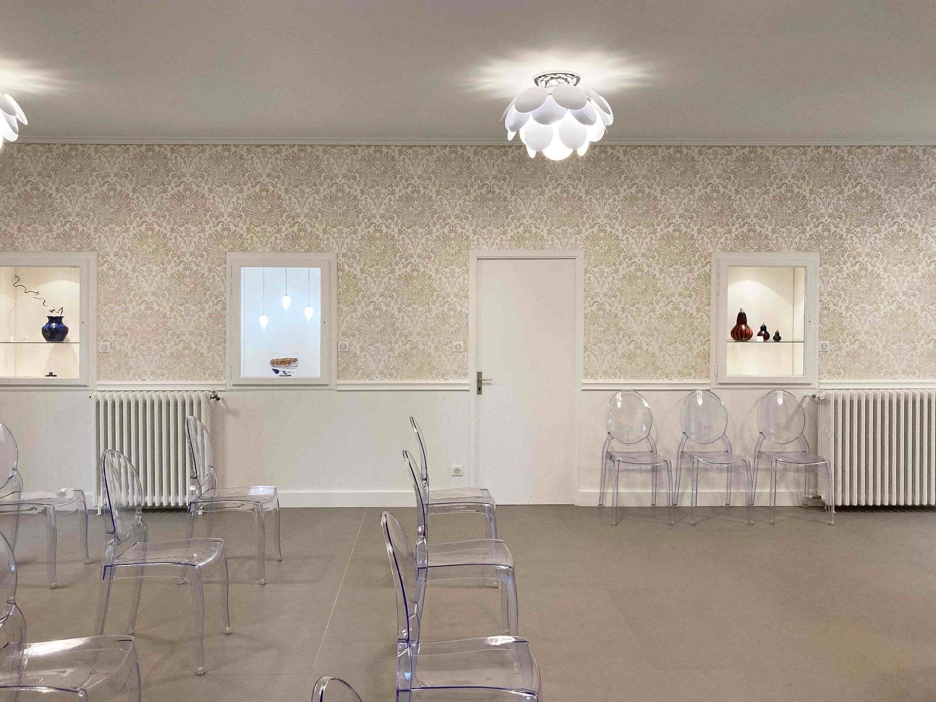 Hall vide décoré avec des chaises transparentes, du papier peint à motifs, des fenêtres, des radiateurs et des plafonniers