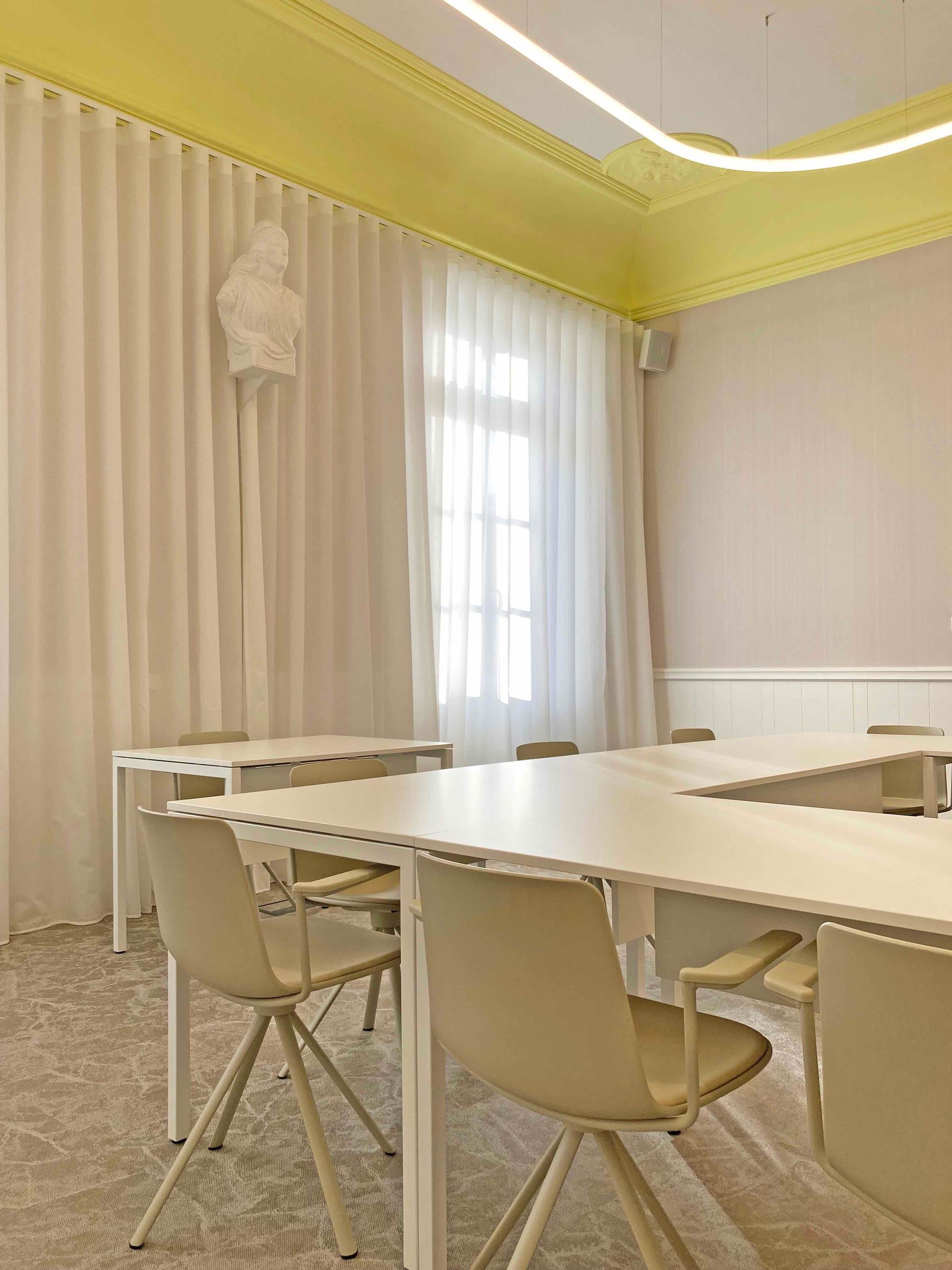 Salle du conseil à Bessines élégante couleur crème avec chaises blanches, longue table, voilages et moulures de plafond jaunes