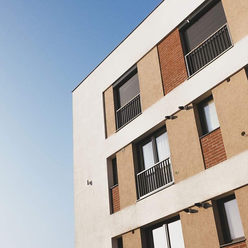 Immeuble d'appartements moderne avec une façade blanche et beige se détachant sur un ciel bleu clair