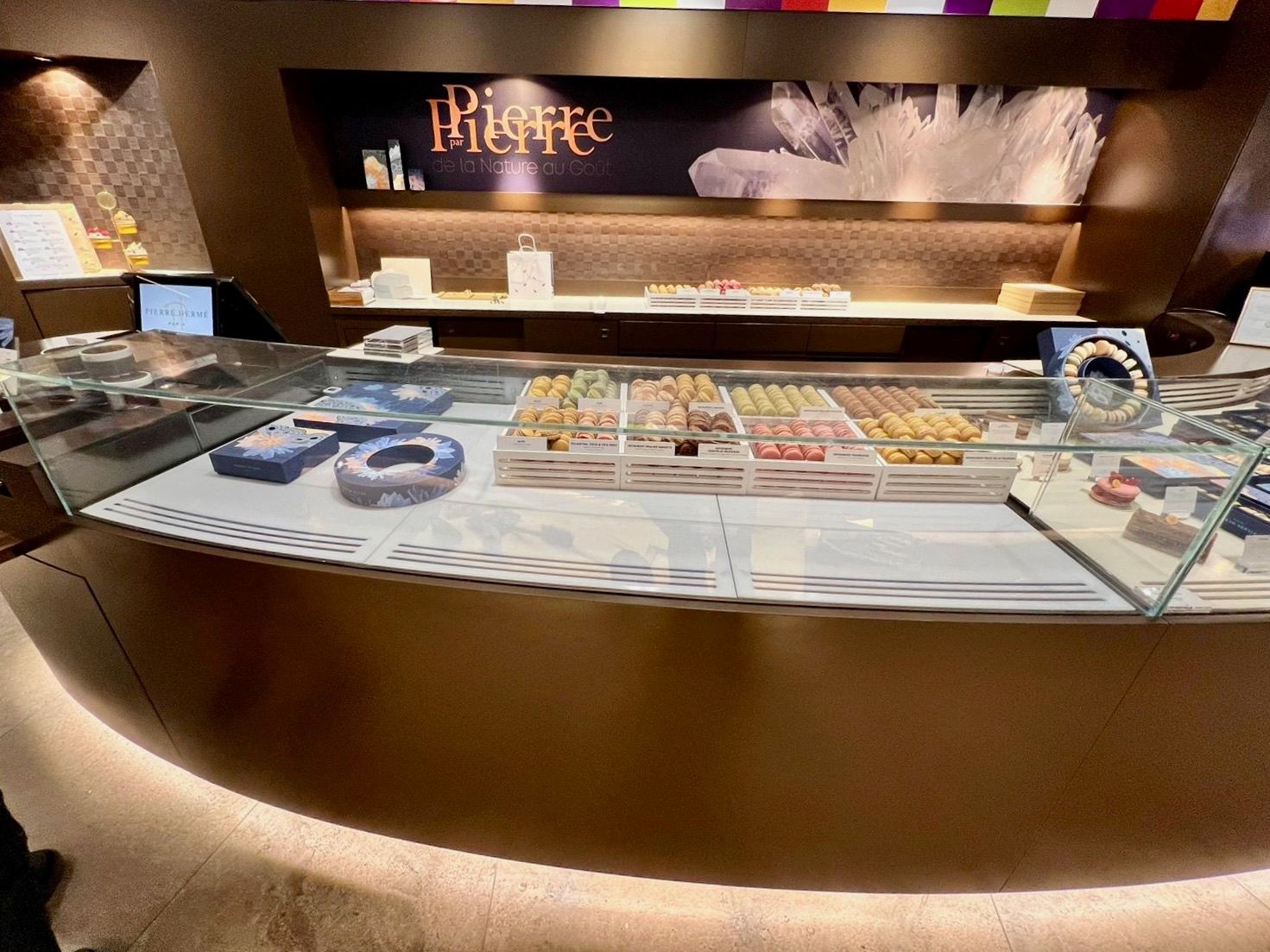 Vitrine à pâtisseries d'une boutique nommée « Pierre », présentant divers desserts colorés.