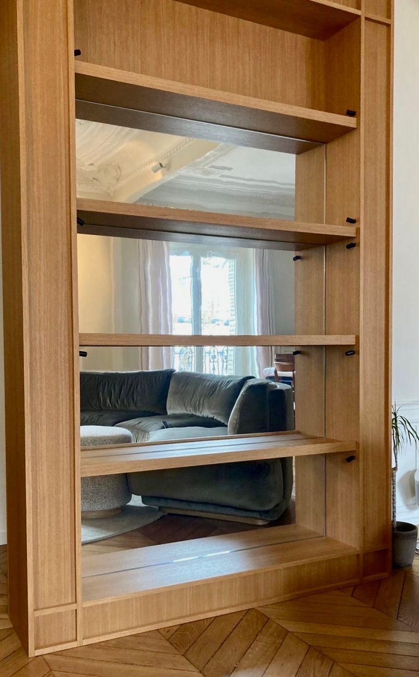 Bibliothèque en bois dont les étagères évoquent un salon avec un canapé.