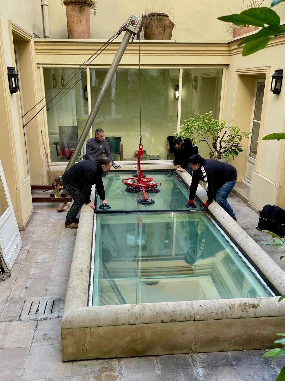 Deux ouvriers installent un grand panneau de verre à l'aide d'un appareil de levage.