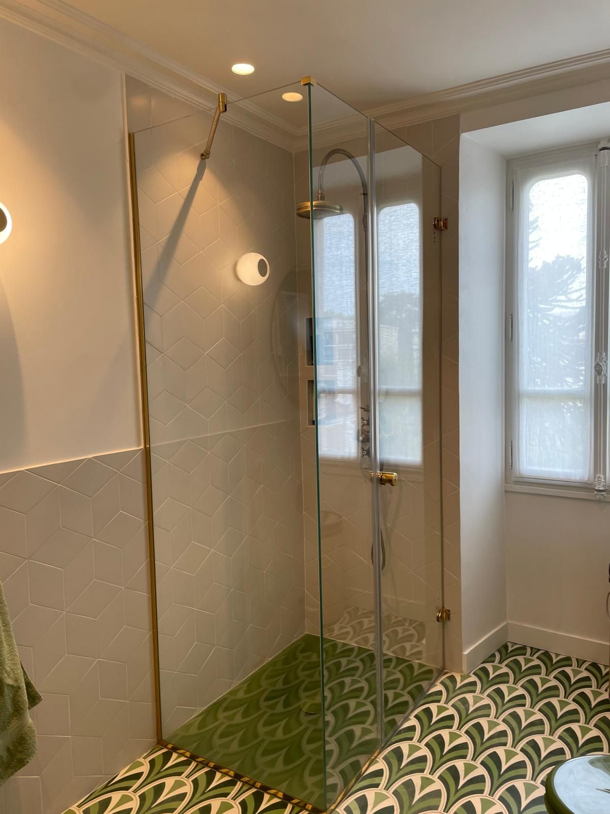 Une salle de bains moderne avec un miroir géométrique rétroéclairé au-dessus d'un lavabo blanc et des accessoires chromés.