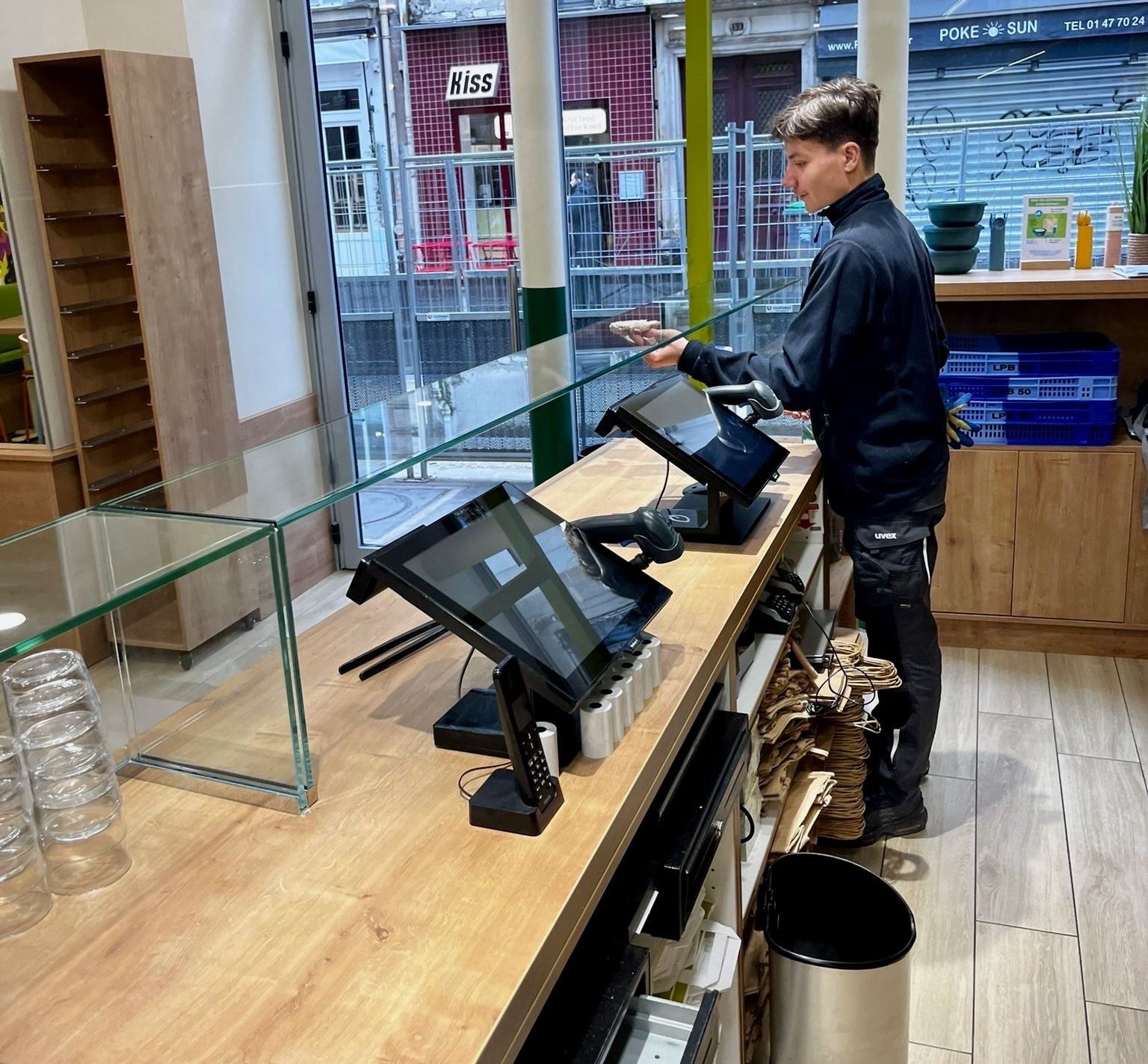 Technicien installant une vitrine sur un comptoir équipé de deux terminaux de paiement.