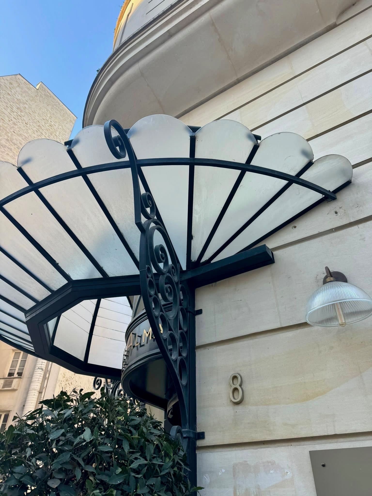 Auvent festonné au-dessus de l'entrée d'un immeuble.