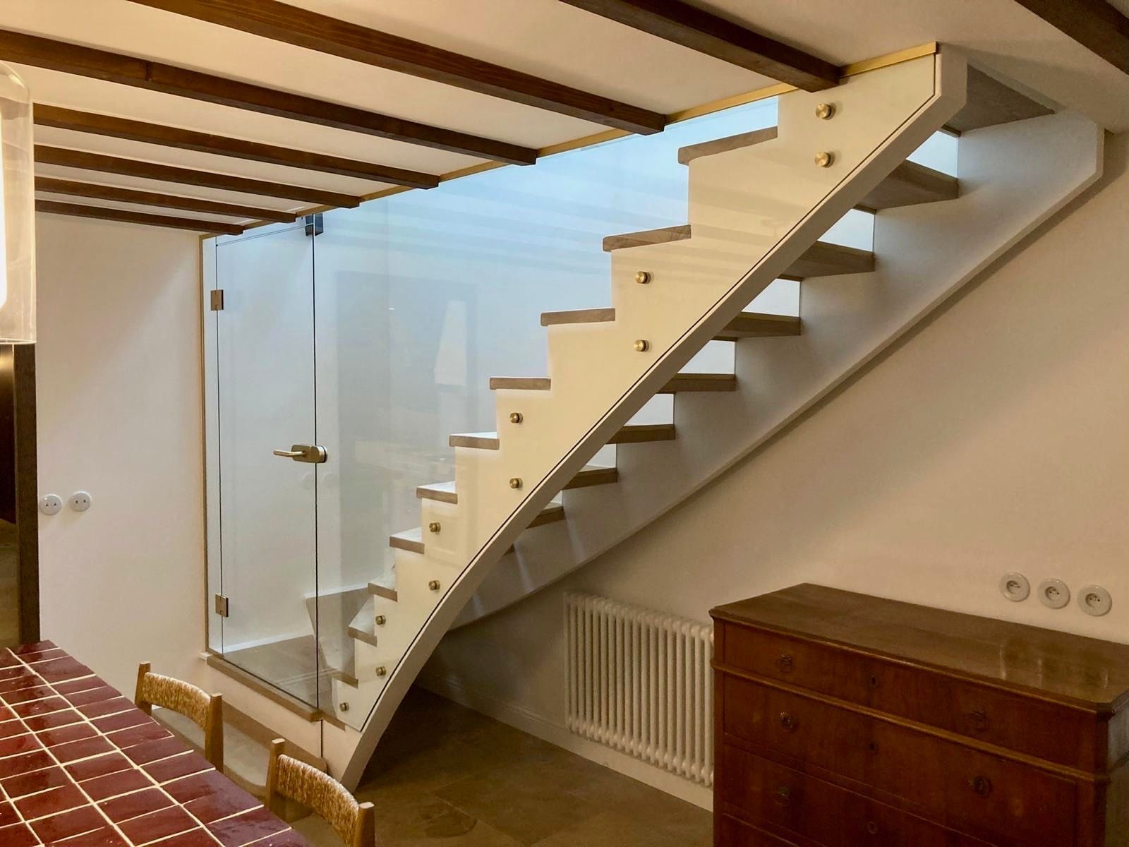 Escalier avec marches en bois et paroi vitrée.