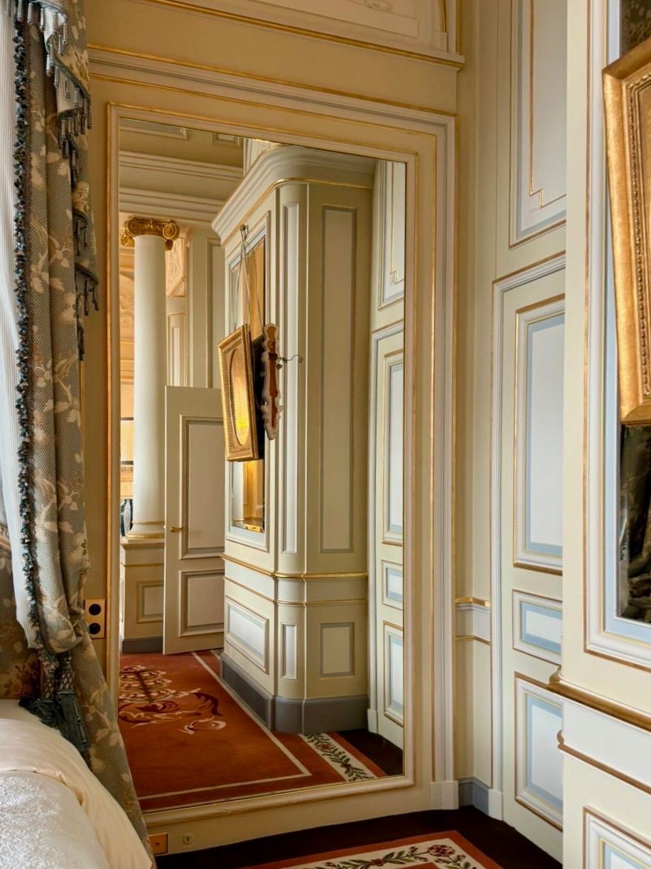 Grand miroir orné, contour crème, avec des garnitures dorées.