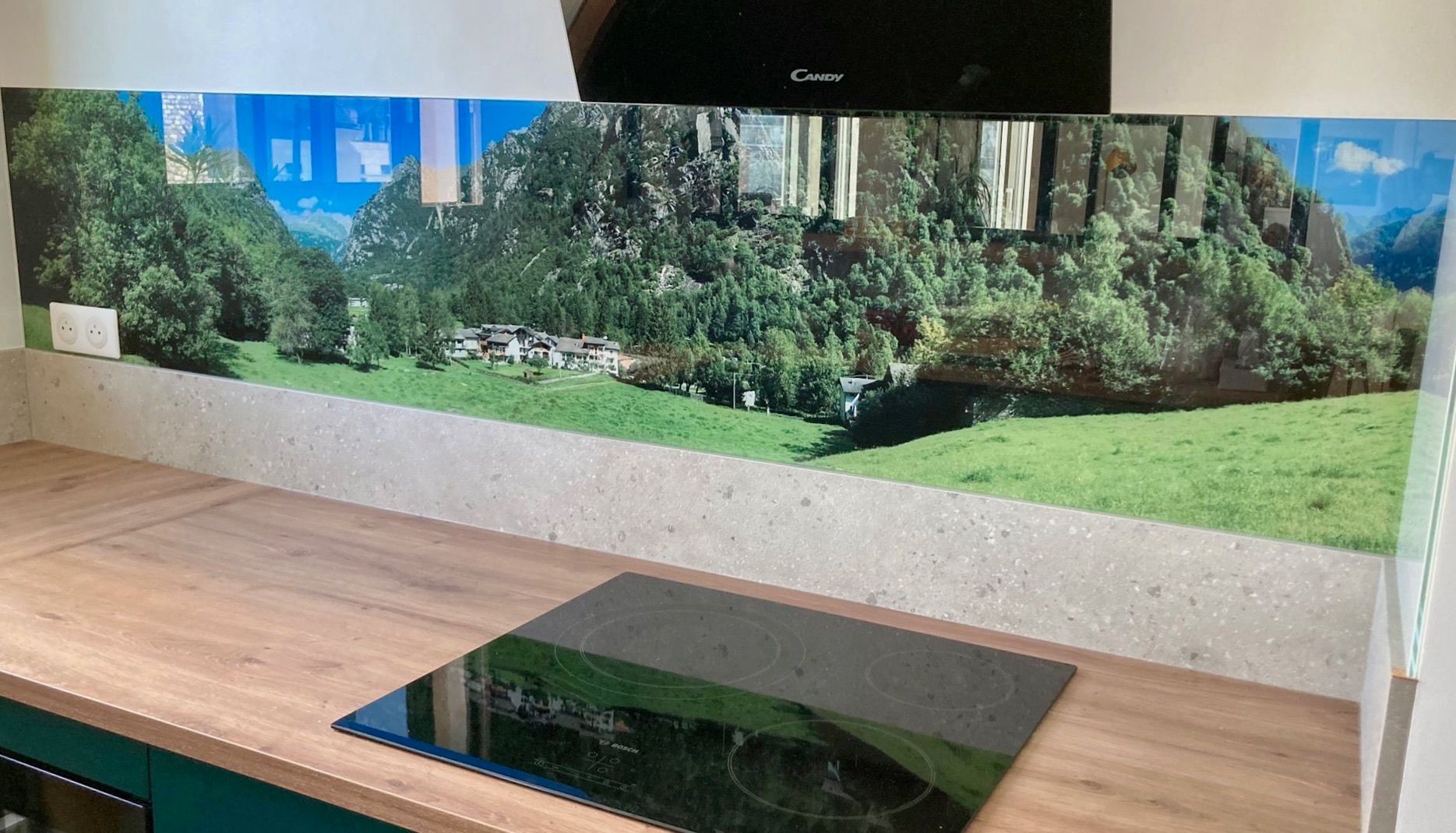 Cuisine avec une crédence décorative, une plaque de cuisson noire et des plans de travail en bois.