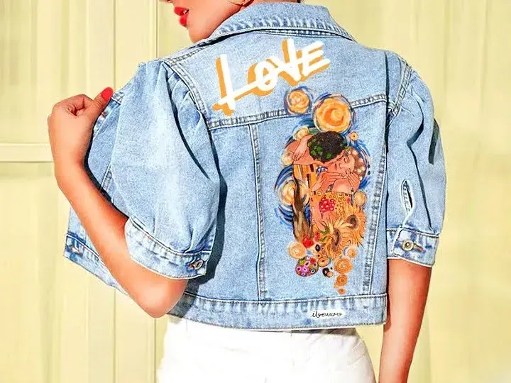 Una mujer lleva una chaqueta vaquera con una pintura en la espalda.