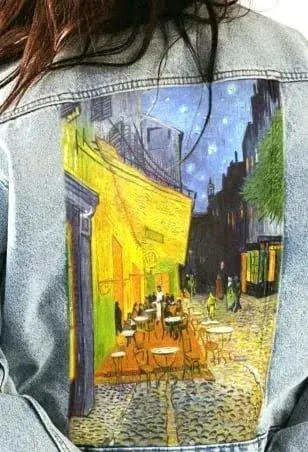 Una mujer lleva una chaqueta vaquera con una pintura en la espalda.