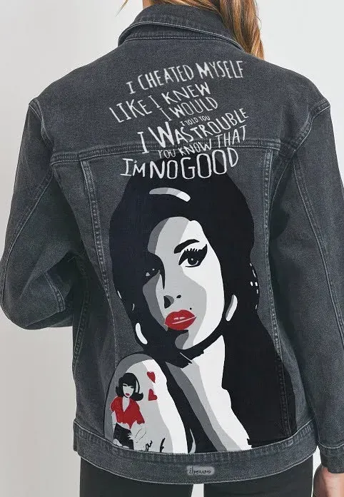 Una mujer lleva una chaqueta vaquera negra con una foto de Amy Winehouse en la espalda.