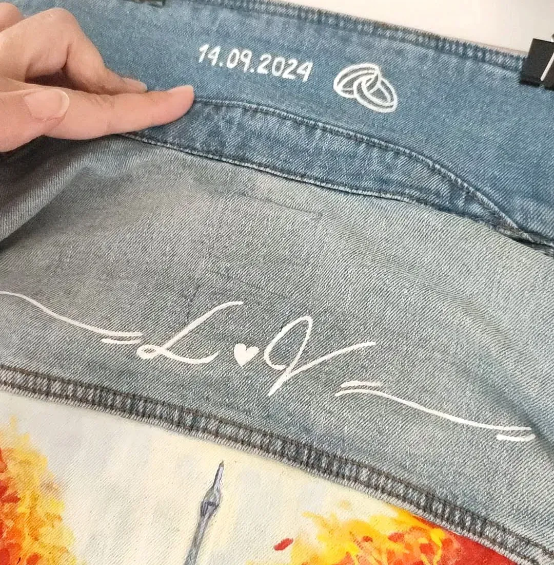 Una persona sostiene una chaqueta vaquera con una pintura en ella.