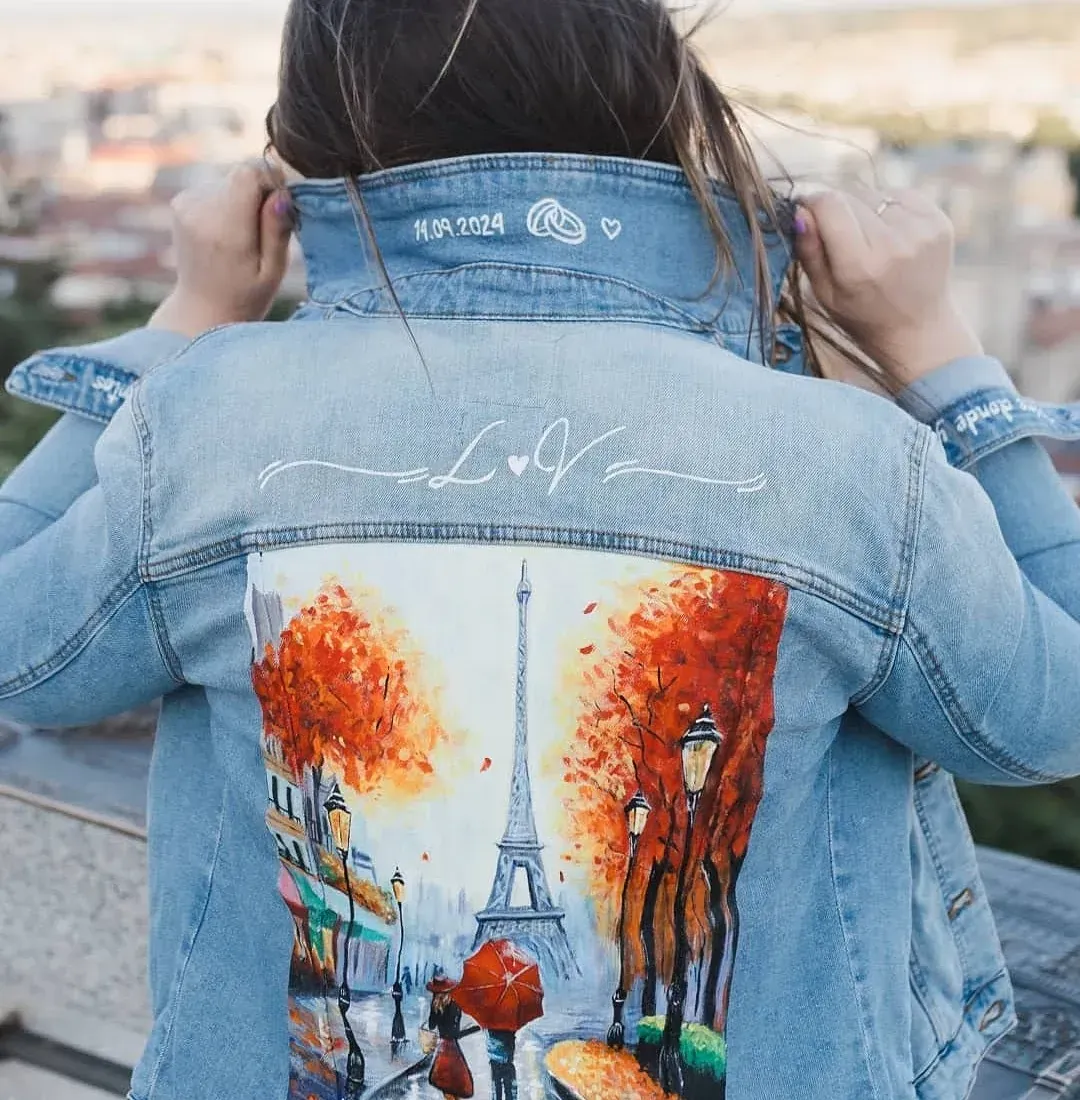 Una mujer lleva una chaqueta vaquera con una pintura de la Torre Eiffel en la espalda.