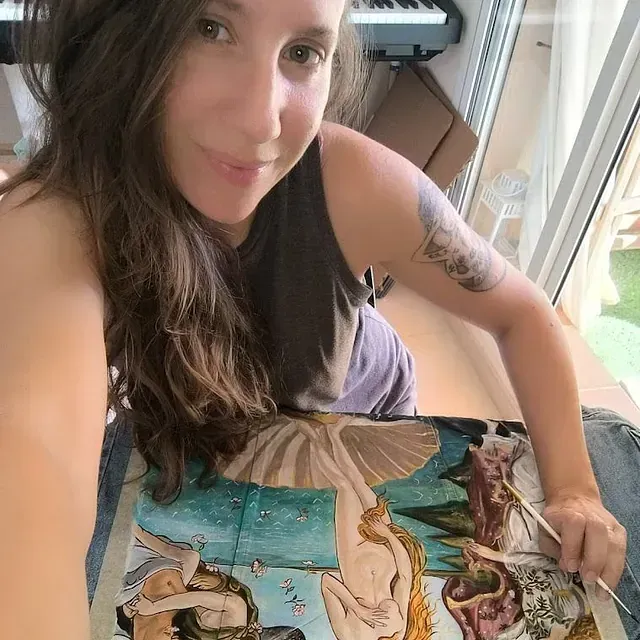 Una mujer se toma un selfie con una pintura en su regazo.