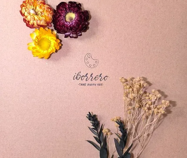 Un ramo de flores secas está sobre una superficie rosa.