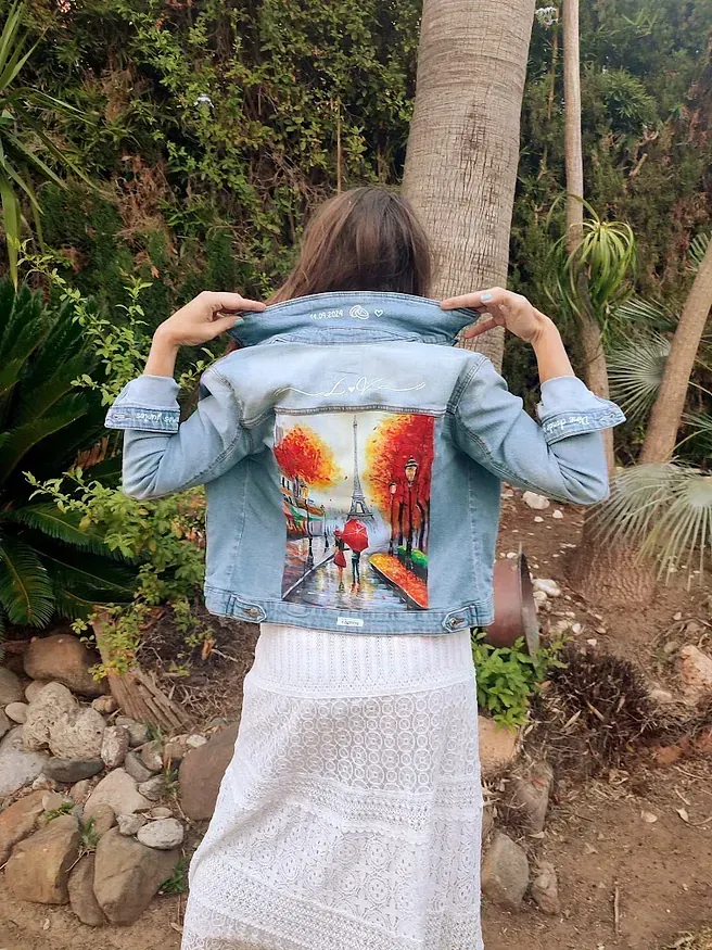Una mujer lleva una chaqueta vaquera con una pintura en la espalda.