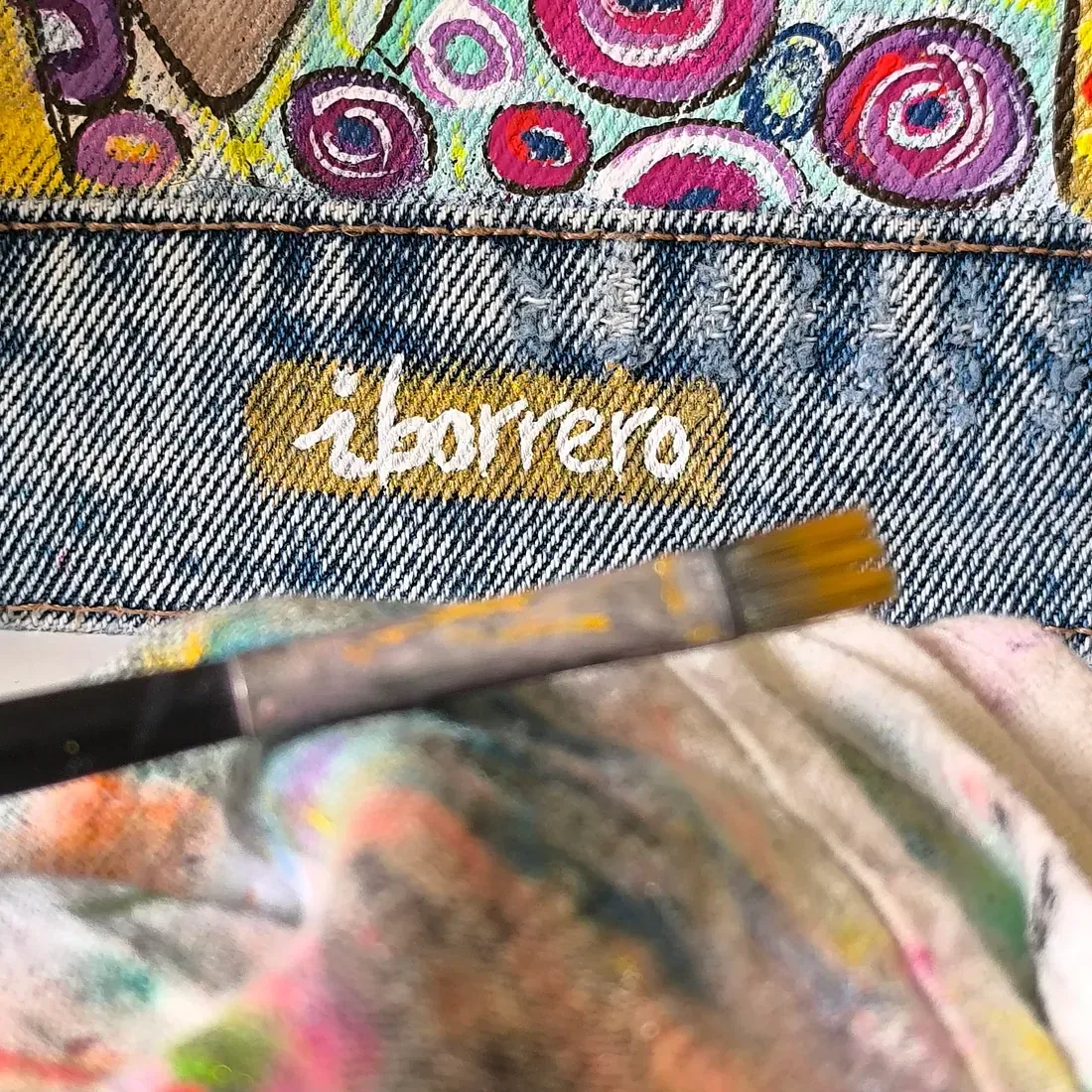 Una persona está pintando un trozo de mezclilla con un pincel.