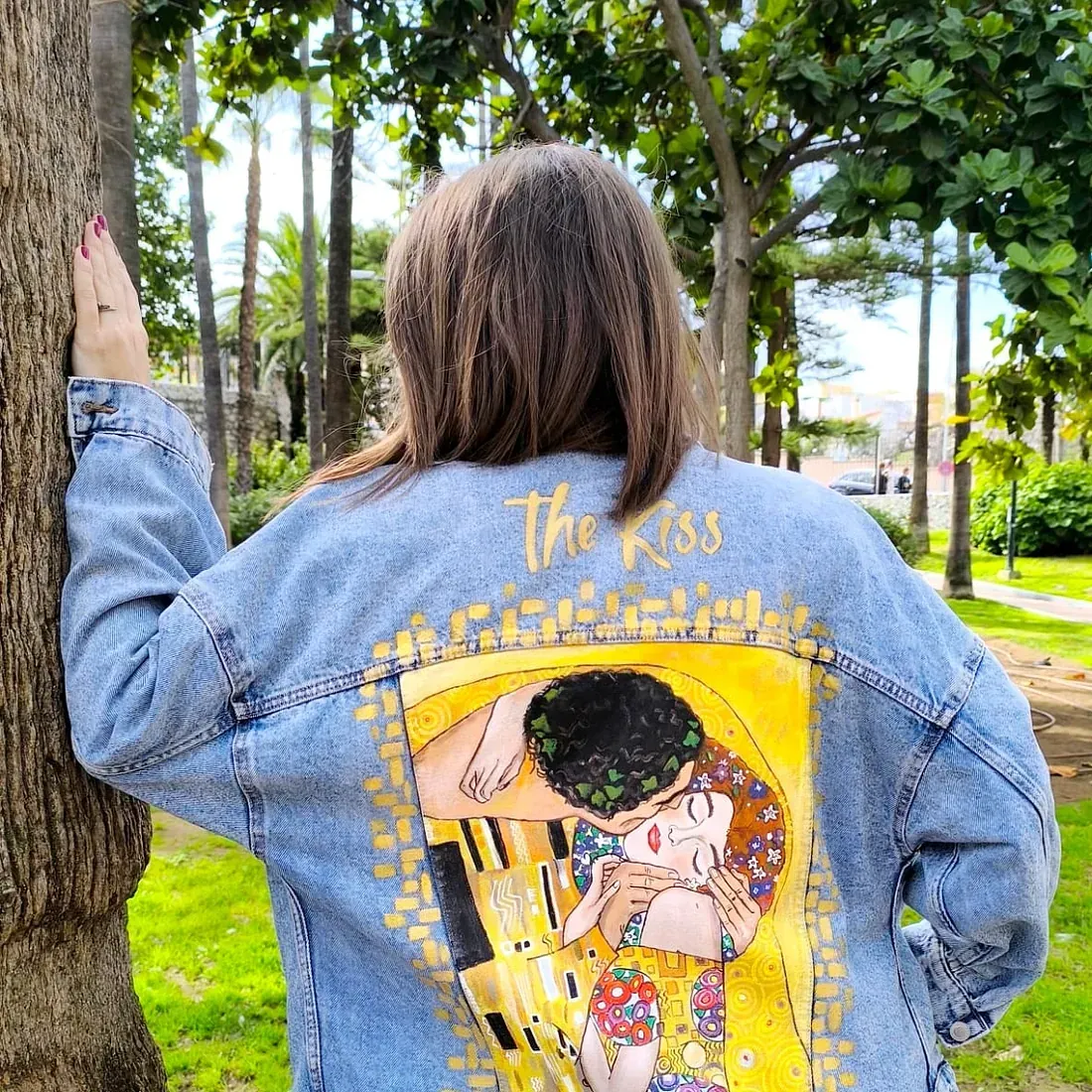 Una mujer lleva una chaqueta vaquera con una pintura del beso en la espalda.