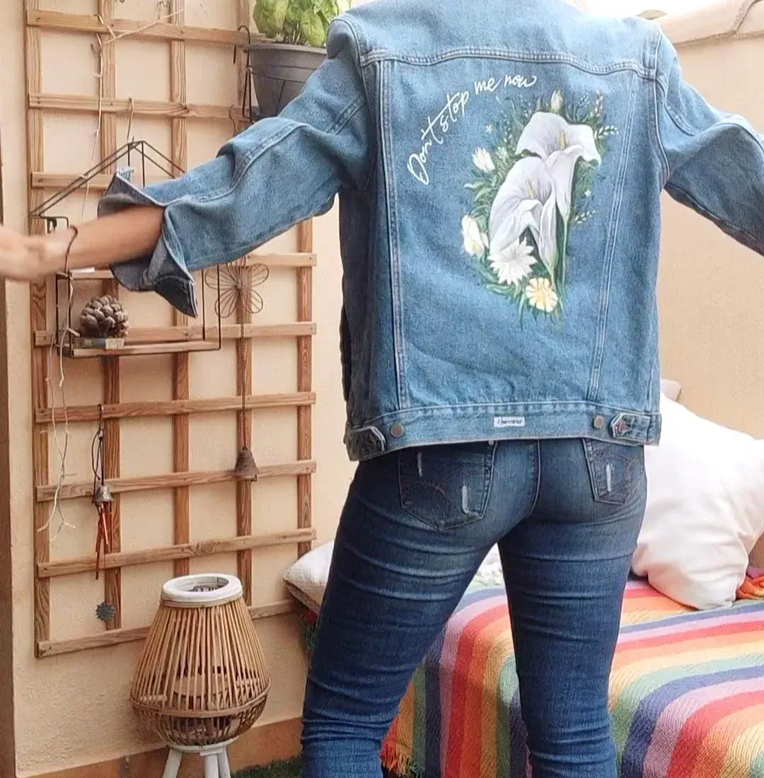 Una mujer que lleva una chaqueta vaquera con flores pintadas.