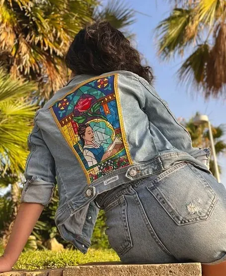 Una mujer que lleva una chaqueta vaquera con una pintura en la espalda.
