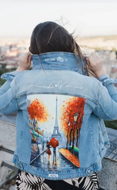 Una mujer lleva una chaqueta vaquera con una pintura en la espalda.