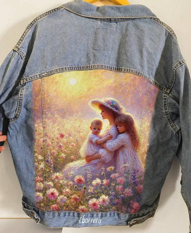 Una chaqueta vaquera tiene una pintura de una mujer sosteniendo a dos niños en la espalda.
