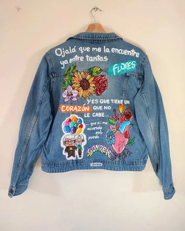 Una chaqueta vaquera con flores pintadas cuelga de una percha.