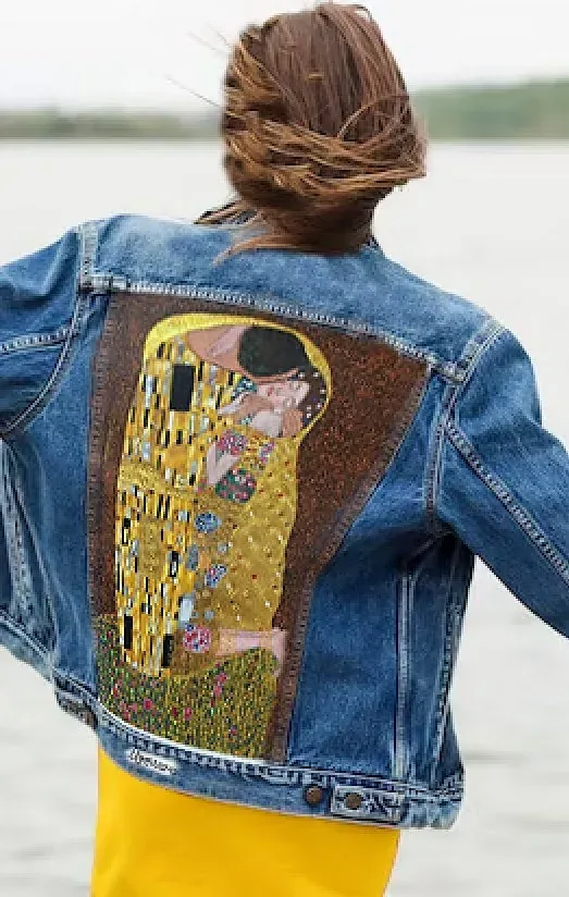 Una mujer lleva una chaqueta vaquera con una pintura del beso en la espalda.