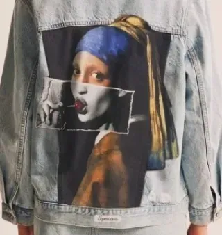Una persona que lleva una chaqueta vaquera con la imagen de una niña con un pendiente de perla en la espalda.