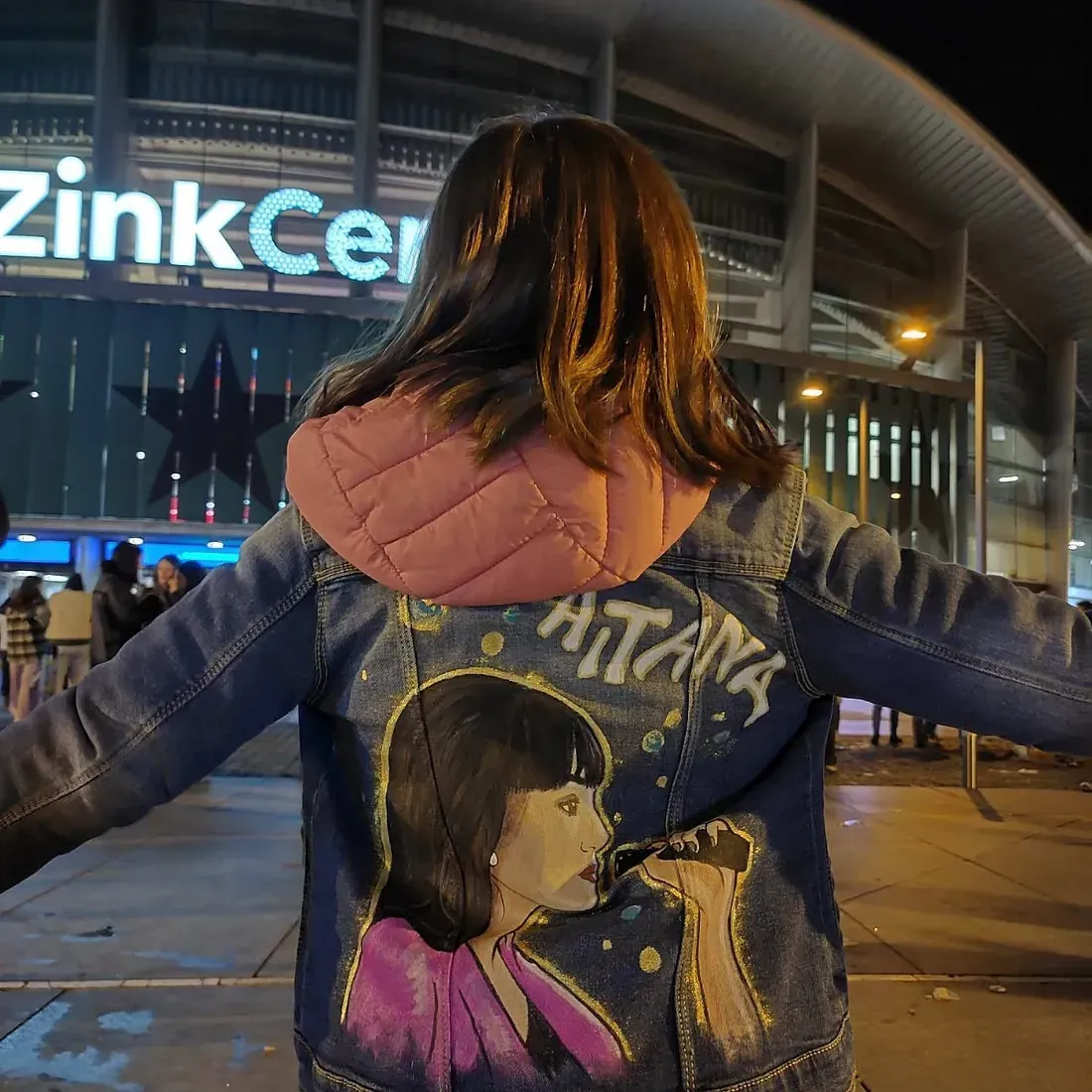 Una mujer que lleva una chaqueta vaquera con una imagen de una mujer en la espalda.