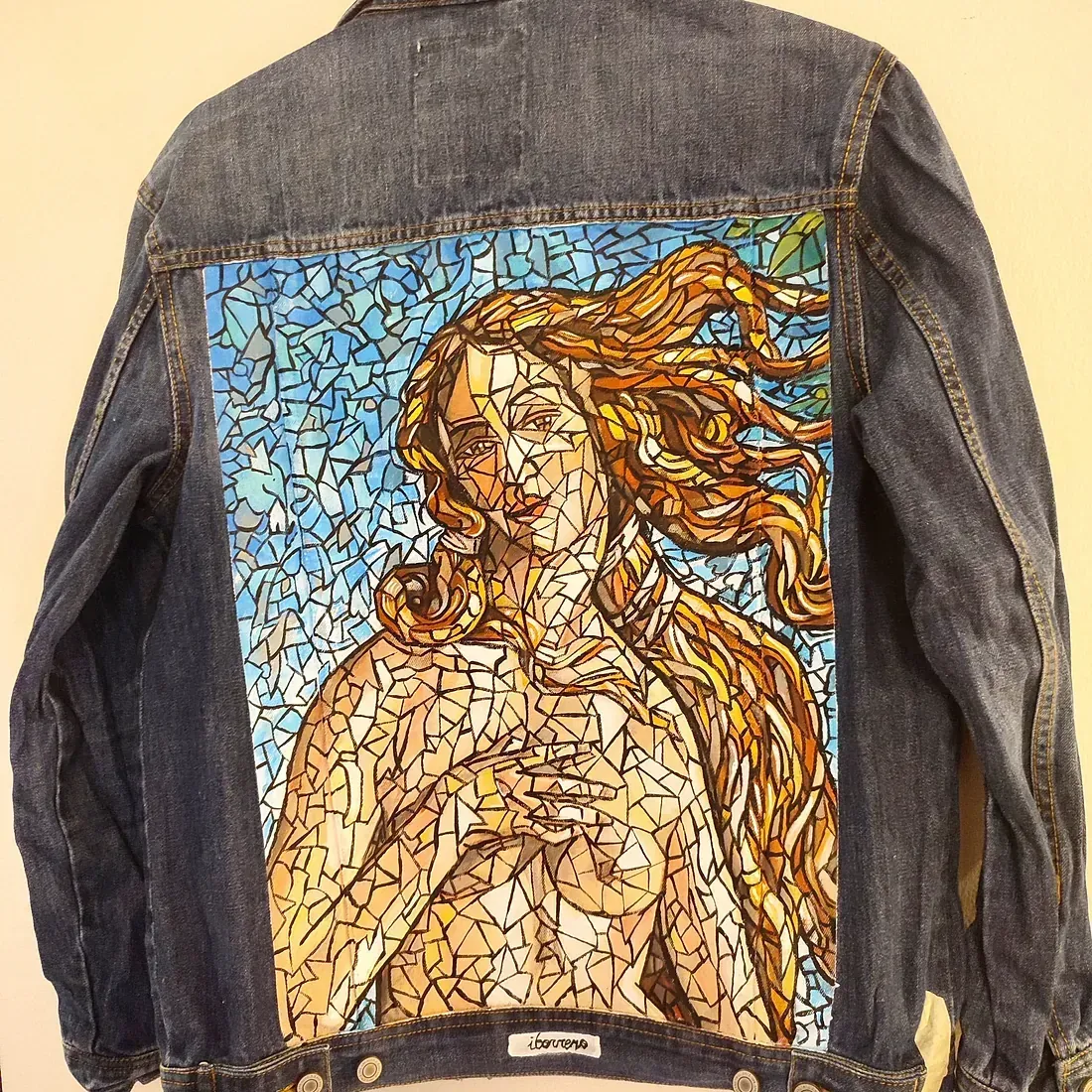 Una chaqueta vaquera con una pintura de una mujer en la espalda.