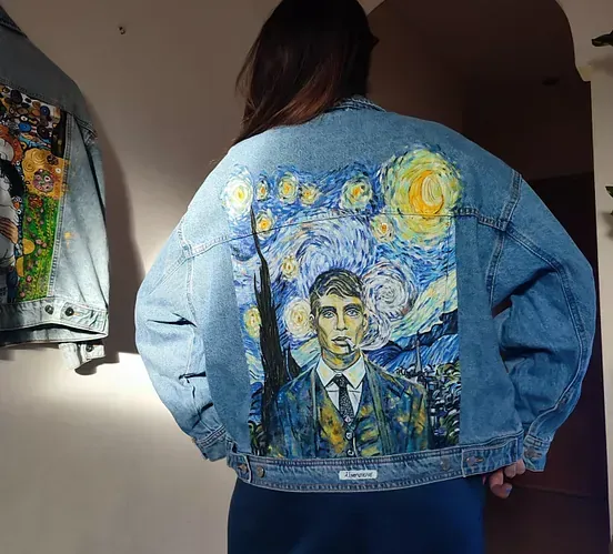 Una mujer lleva una chaqueta vaquera con una pintura de una noche estrellada en la espalda.