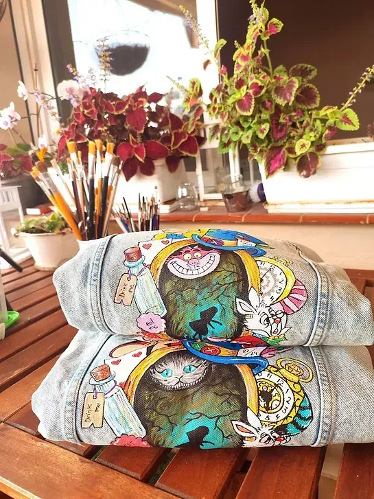 Dos chaquetas de mezclilla están apiladas una encima de otra sobre una mesa de madera.