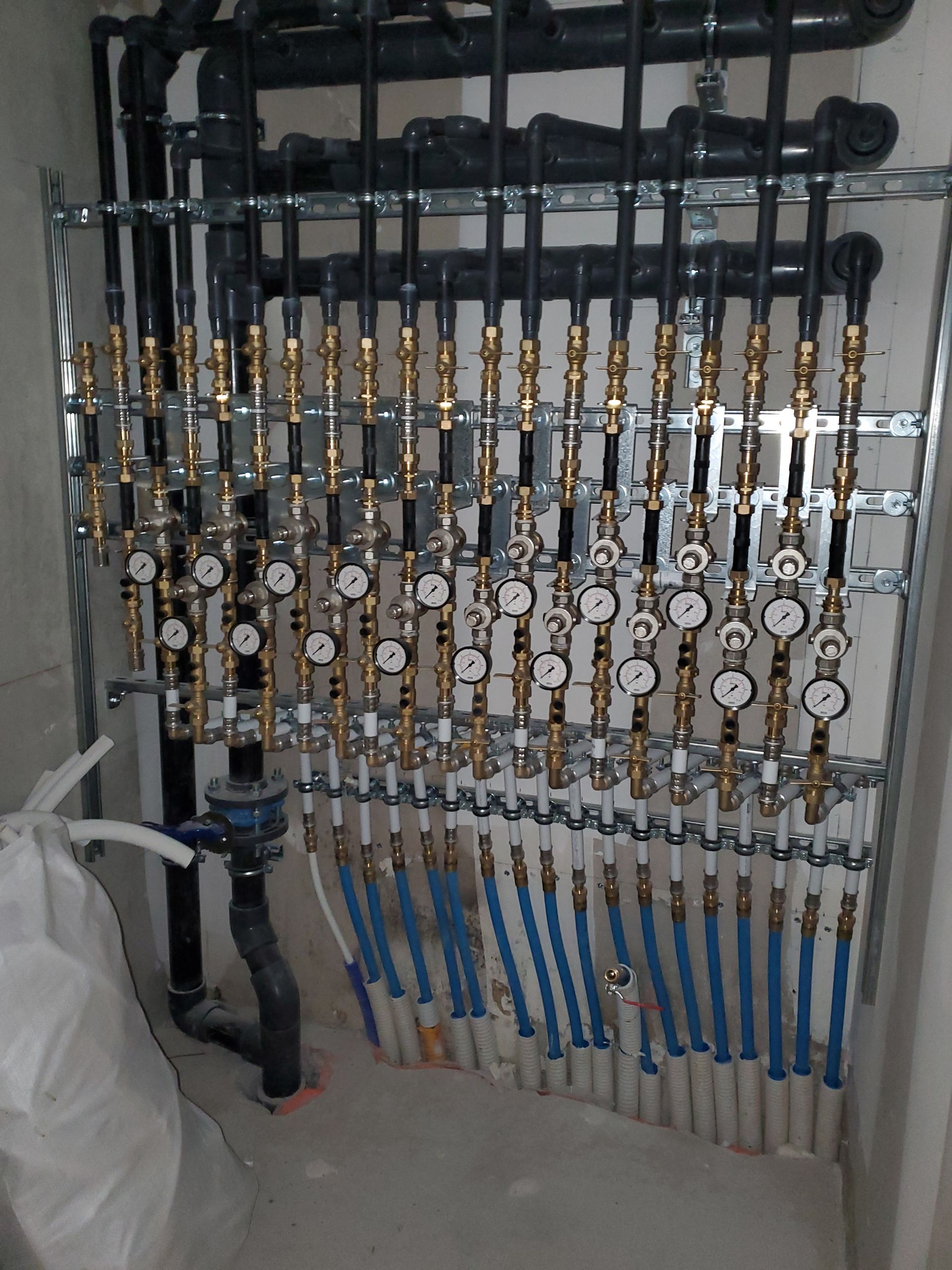 Collecteur de vannes industrielles avec rangées de tuyaux et manomètres dans une salle des machines