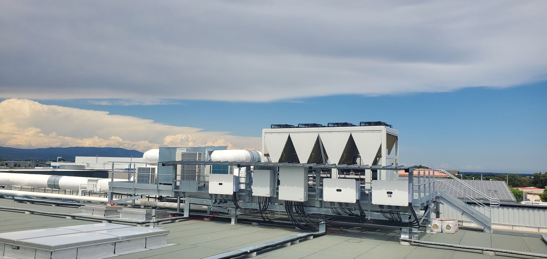 Site industriel avec de grands bâtiments blancs et des unités sur le toit sous un ciel nuageux