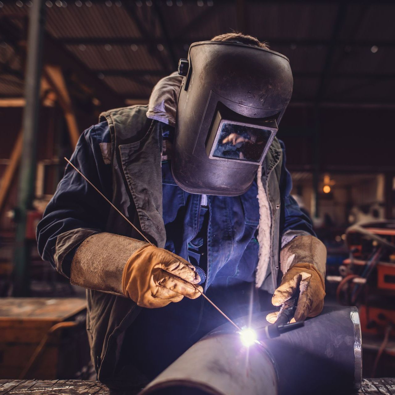 Un soudeur avec un masque et des gants de protection