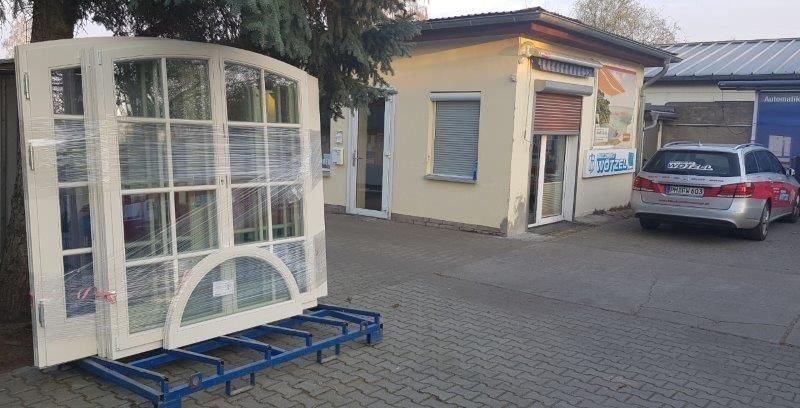 Vor einem Gebäude neben einem großen Fenster parkt ein Auto.
