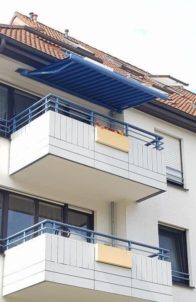Ein Balkon mit einer blauen Markise darüber